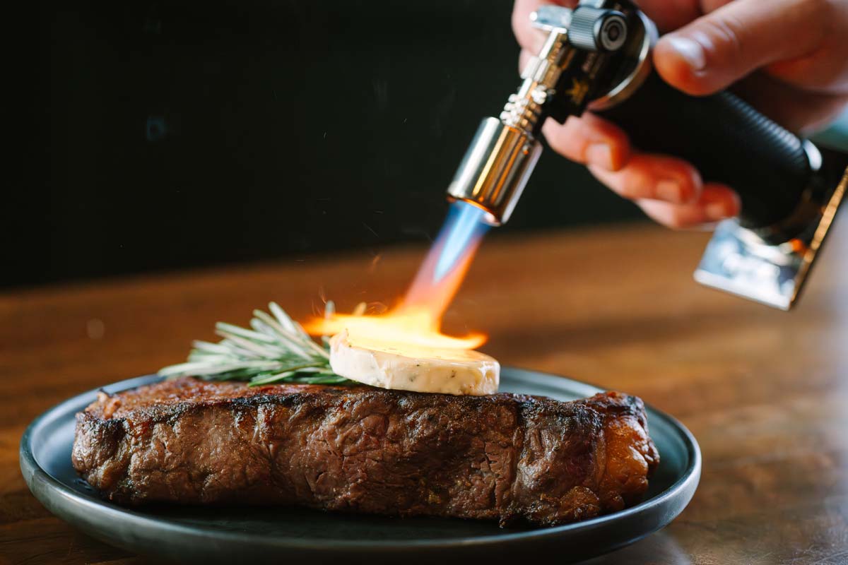 Mini torch melting flavored butter over steak | Gio's Prime 26